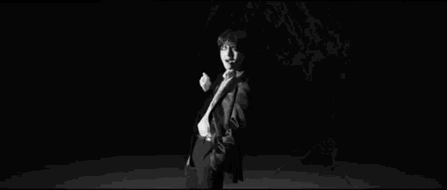 a black and white photo of a man in a suit and tie standing in front of a white background .