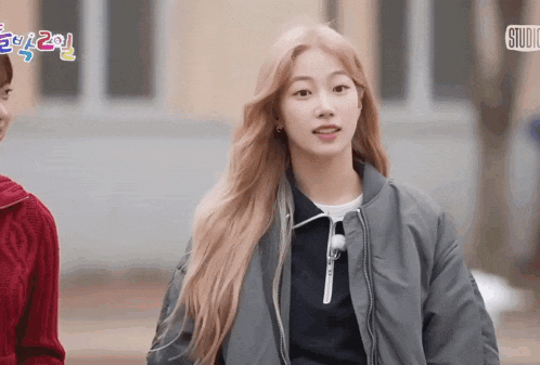 a girl in a grey jacket stands in front of a sign that says ' studio ' on it