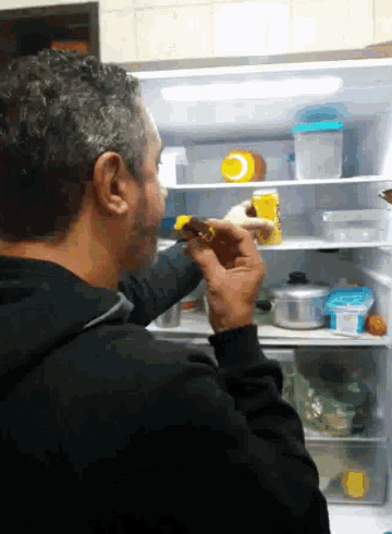 a man is taking something out of a refrigerator that has a yellow container in it