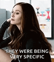 a woman with long hair is sitting at a table with her hand on her head and the words `` they were being very specific ''