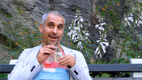a man sitting on a bench holding a bottle of cologne