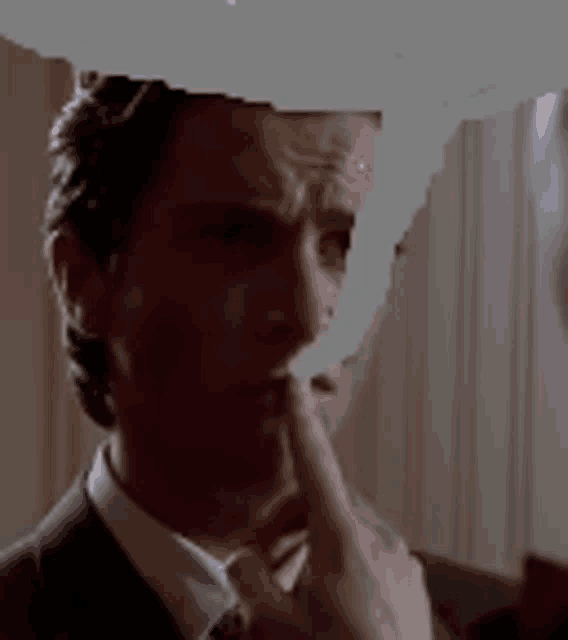 a man in a suit and tie is holding his finger to his chin