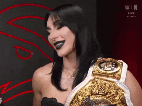 a woman is wearing a wrestling belt and has black lipstick on .