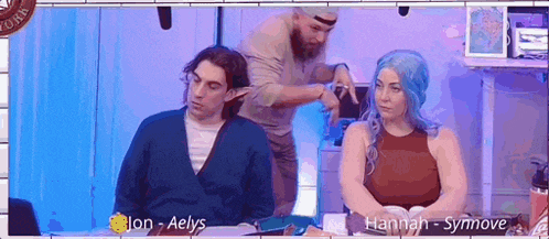 a man is cutting a woman 's hair while she sits next to a man with a beard .