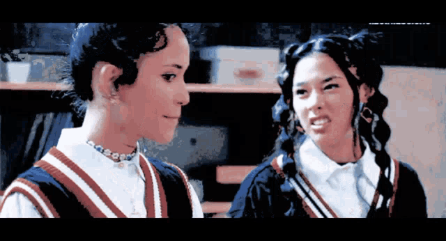 two girls are standing next to each other and one is making a face