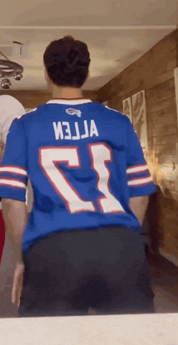 a man is wearing a buffalo bills jersey and dancing in front of a mirror .