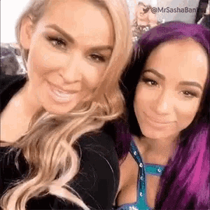 two women with purple hair are posing for a picture together and smiling .