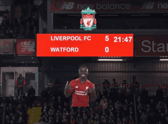 a liverpool fc player giving a thumbs up in front of a scoreboard that says watford