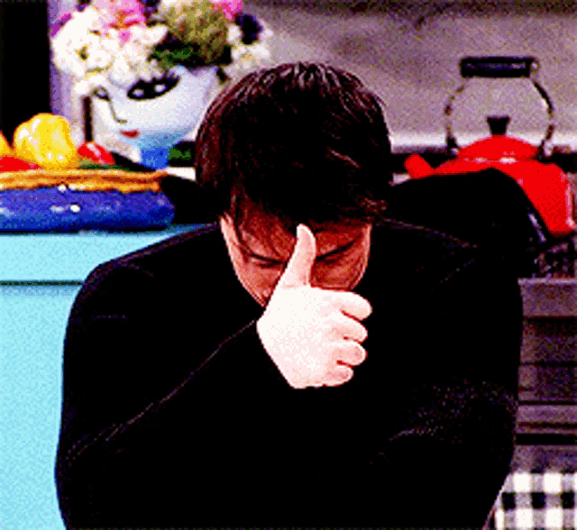 a man in a black sweater is giving a thumbs up sign