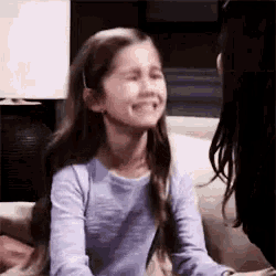 a little girl is crying while sitting on a couch with her mother .