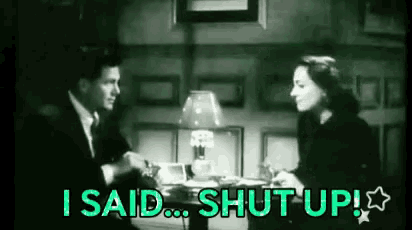 a man and a woman are sitting at a table with the words `` i said shut up '' written in green .