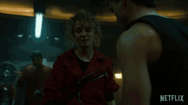 a man in a black tank top stands next to a woman in a red jacket with netflix written on the bottom right
