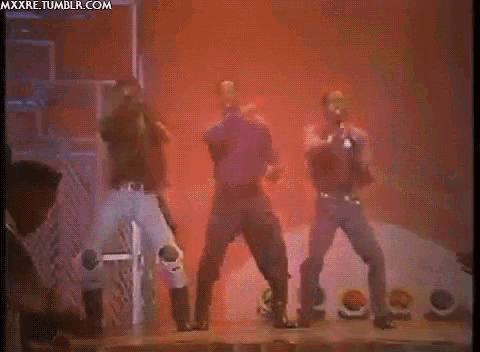 a group of men are dancing on a stage in front of a smokey background
