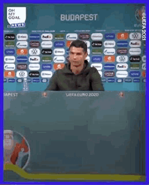 a man is holding a bottle of water in front of a uefa euro 2020 advertisement .