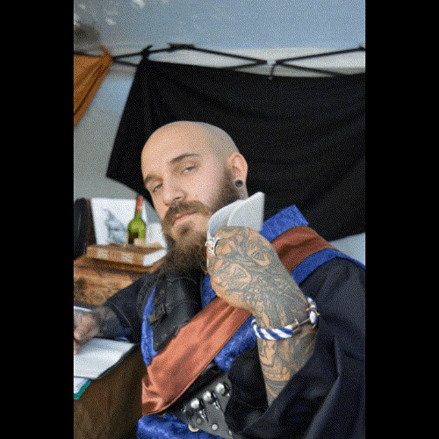 a man with a beard and a tattoo on his arm is holding a piece of paper