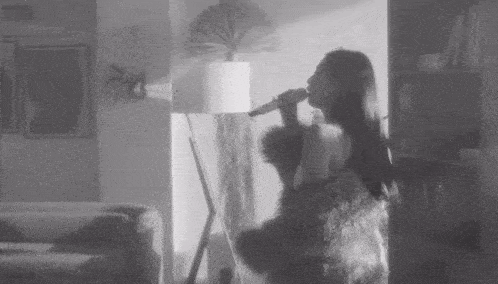 a woman is singing into a microphone in a black and white photo .