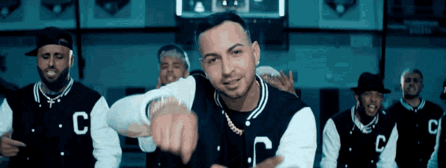 a man wearing a black and white varsity jacket with the letter c on it