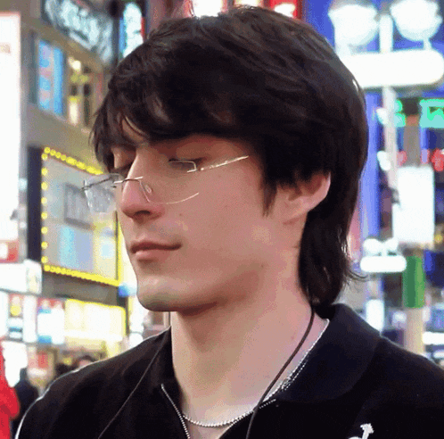 a close up of a man wearing glasses and a necklace with the letter a on it