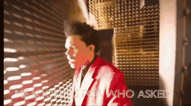 a man in a red suit is walking down a hallway with the words " me looking for who asked " behind him