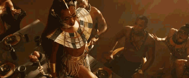 a woman in a gold dress is surrounded by other men