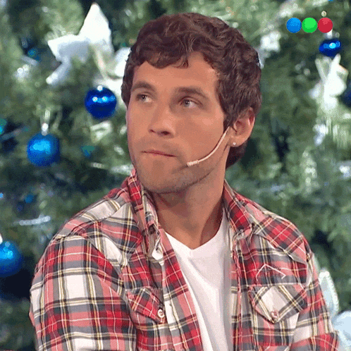 a man wearing a plaid shirt has a microphone on his head