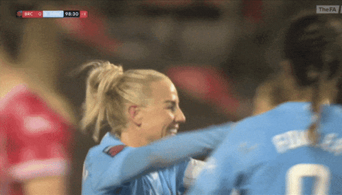 two female soccer players are hugging each other during a game with bbc on the bottom left