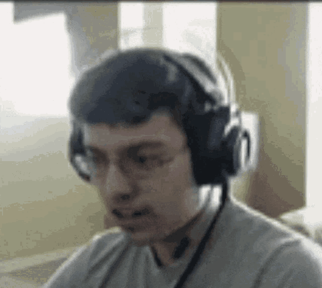 a man wearing headphones and a microphone is sitting in front of a computer screen .