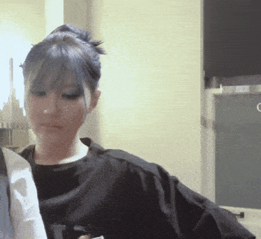 a woman with blue hair is wearing a black shirt with the letter t on it