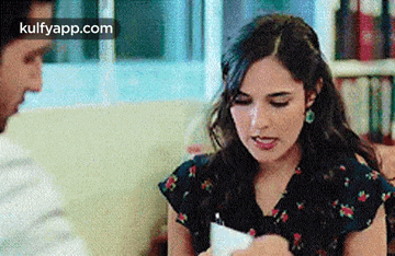 a man and a woman are sitting on a couch talking to each other .