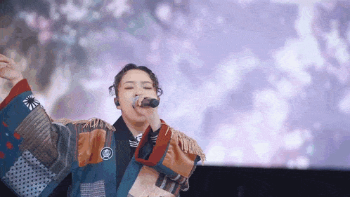 a woman in a kimono singing into a microphone in front of a screen