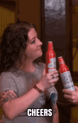 a woman is holding two budweiser bottles and the word cheers is on the bottom
