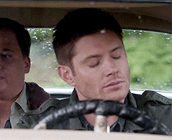 a man with his eyes closed is driving a car with another man in the back seat