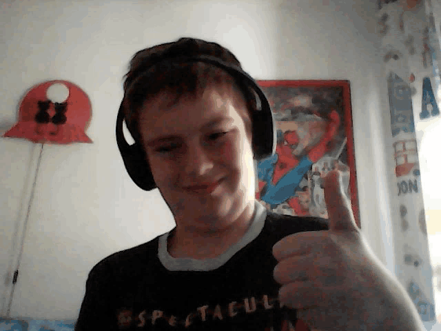 a boy wearing headphones giving a thumbs up