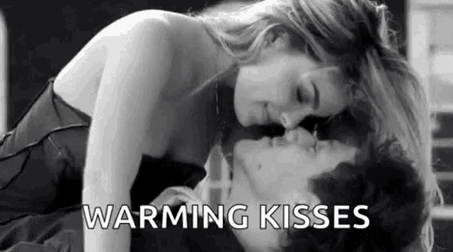 a man and a woman are kissing in a black and white photo with the words `` warming kisses '' .