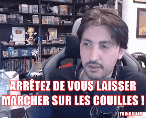 a man sitting in front of a microphone with the words " arretez de vous laisser marcher sur les couilles " above him