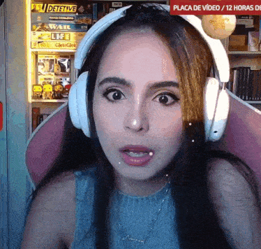 a woman wearing headphones is sitting in front of a sign that says placa de video 12 horas de