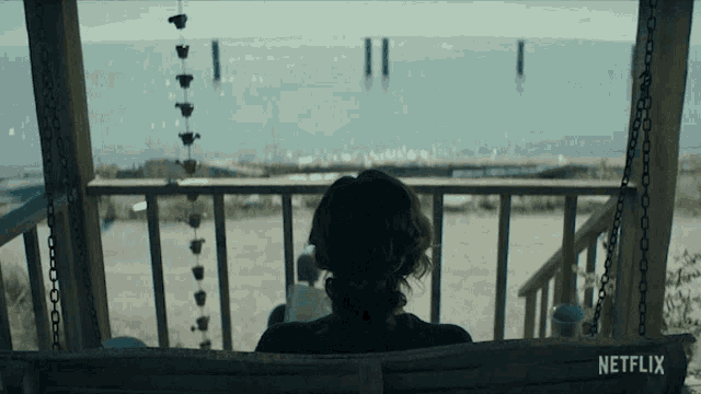 a woman sits on a porch swing with a netflix logo visible