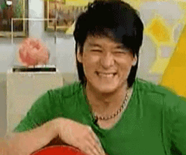 a man in a green shirt is smiling while sitting on a red chair .