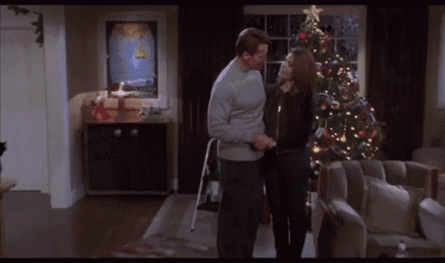 a man and a woman are standing in front of a christmas tree