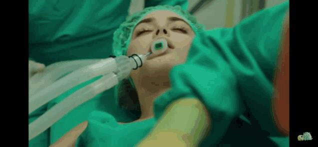 a woman in an operating room with an anesthesia mask on her face
