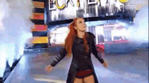 a woman with red hair is standing on a stage with her arms outstretched in front of a sign .