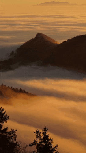 a view of a mountain covered in fog and clouds