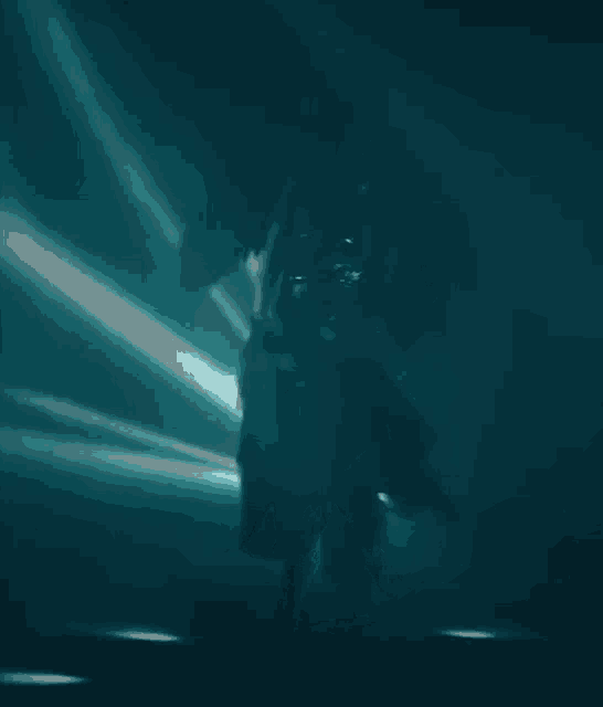 a silhouette of a person in a dark room with a light behind them .