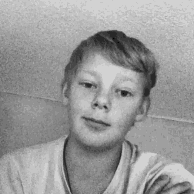 a young boy in a white shirt is taking a selfie .