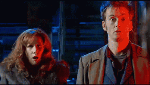 a man and a woman are standing next to each other in a dark room with red light behind them