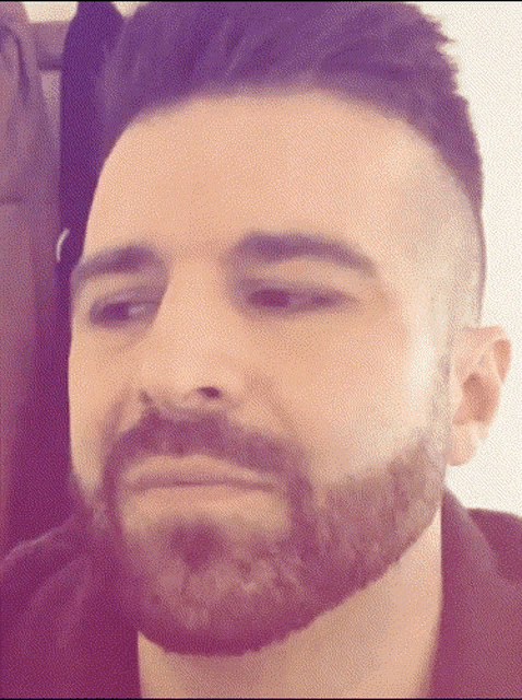 a man with a beard and shaved head looks at the camera
