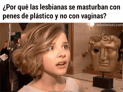 a young girl is standing in front of a statue of a man 's head and a question in spanish
