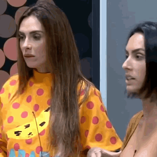 two women are standing next to each other and one has a yellow shirt with red polka dots