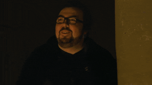 a man with glasses says " i do want to win " in a dark room