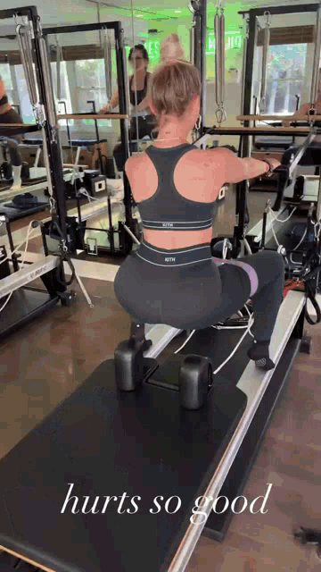 a woman is squatting on a pilates machine with the words hurts so good below her